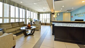 A hotel lobby with a reception desk, a sofa, armchairs, and a coffee table.