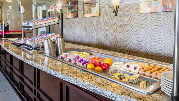 A buffet counter with various food items, including fruits, pastries, and beverages.