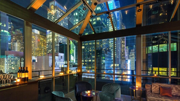 A modern interior with a glass ceiling, seating area, and a bar with bottles and glasses.