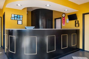 A reception desk with a black and yellow color scheme, a clock, and a mounted television. - Econo Lodge Inn & Suites near Chickamauga Battlefield (Fort Oglethorpe)