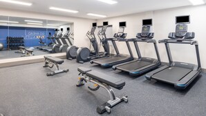 Une salle de sport équipée de tapis de course, de vélos elliptiques et de poids libres.