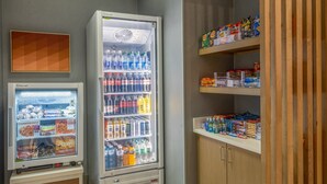 Un distributeur automatique proposant une variété de collations et de boissons, un congélateur rempli d’aliments surgelés et une étagère avec des produits emballés.
