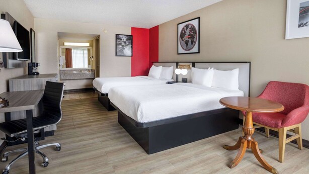 A hotel room with a bed, desk, chair, and a round wooden table. - Ramada by Wyndham Rome / Verona (Rome)