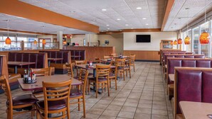 A restaurant interior with booths and tables, a counter, and a TV on the wall. - Ramada by Wyndham Rome / Verona (Rome)