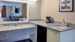 A hotel bathroom with two sinks, a mirror, a coffee maker, and a framed picture of the Statue of Liberty. - Ramada by Wyndham Rome / Verona (Rome)