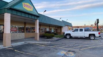 Un restaurante Denny's con techo verde y una camioneta pickup blanca estacionada al frente.