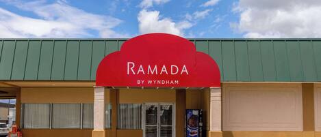 Liiketila, jonka yläpuolella on punainen markiisi, jossa lukee ”RAMADA BY WYNDHAM”, ja sen edessä on Pepsi-automaatti.