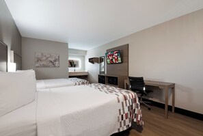 Una camera d'albergo con due letti, una scrivania, una sedia, un televisore e una finestra.