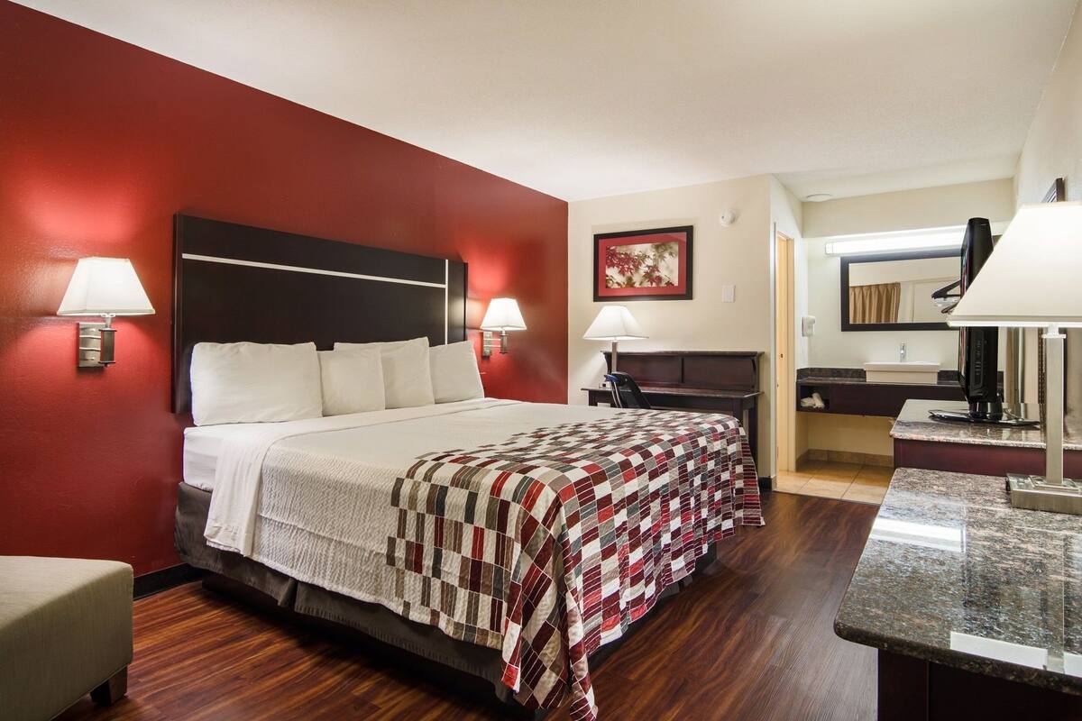 Hotelkamer met een bed, nachtlampjes, een bureau, een stoel, een spiegel en een koffieapparaat.