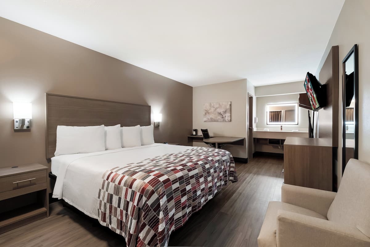 Hotellihuone, jossa on suuri sänky, työpöytä, tuoli ja televisio.