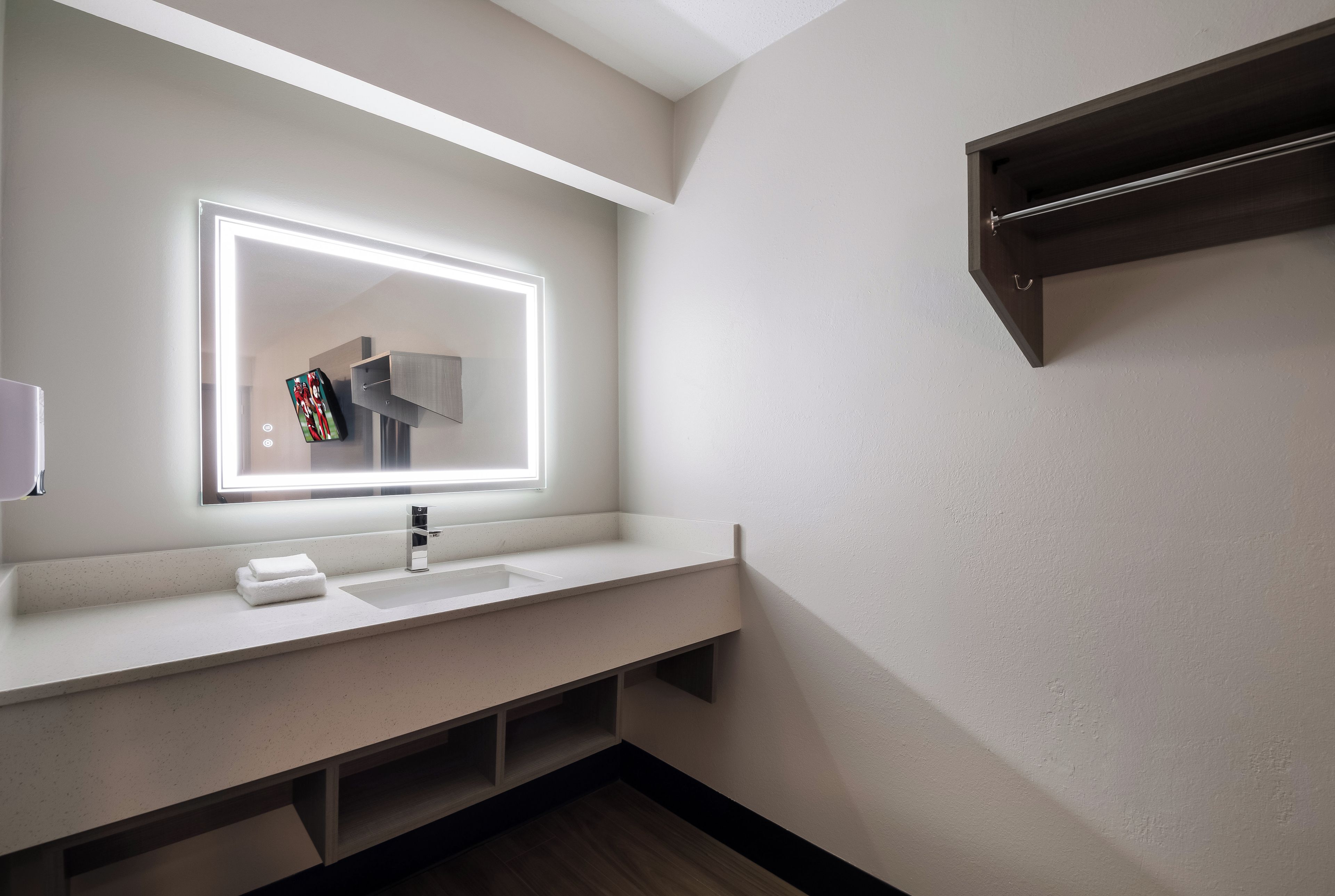 Un baño moderno con un espejo grande, un lavamanos y un perchero para toallas.
