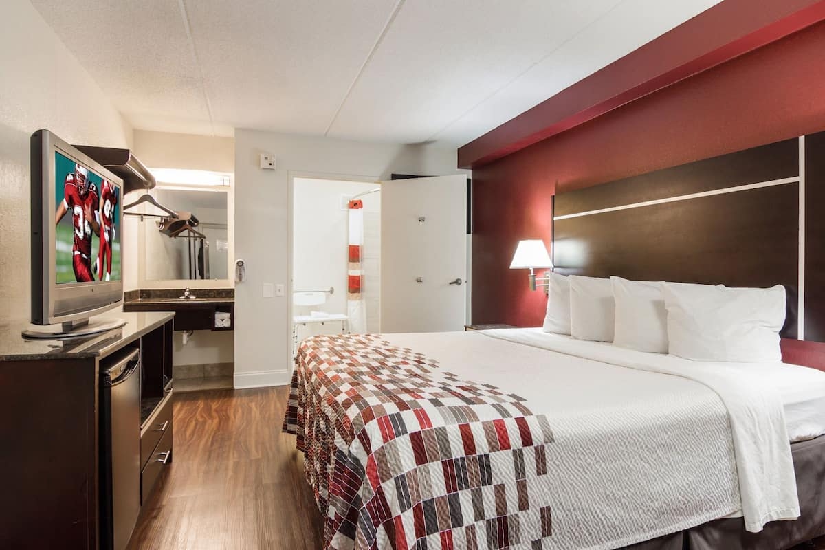 Hotellihuone, jossa on sänky, televisio, työpöytä ja kylpyhuone.