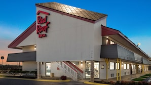 A Red Roof Inn with a modern design, featuring a prominent red and white color scheme, a covered outdoor area, and a staircase leading to the entrance. - Red Roof Inn Chattanooga - Hamilton Place (Chattanooga)