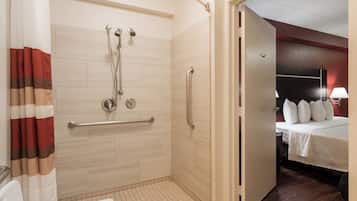 A hotel bathroom with a shower, grab bars, and a toilet.