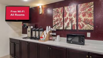A kitchenette with a coffee machine, microwave, and a sign indicating free Wi-Fi in all rooms.