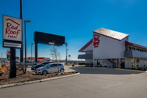Ett Red Roof Inn-motell med klar himmel, en parkeringsplats och en reklamskylt.