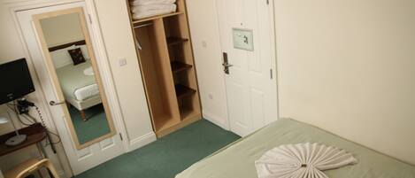 Une pièce comprenant un lit, un bureau, une chaise, une armoire et une porte.