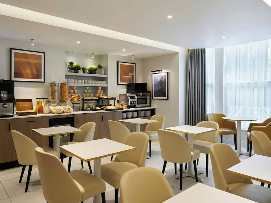 A modern cafe with a counter, seating area, and large windows.