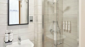 Ein modernes Badezimmer mit einer gläsernen Duschkabine, einem Waschbecken und zwei Flaschen Activ Seife.
