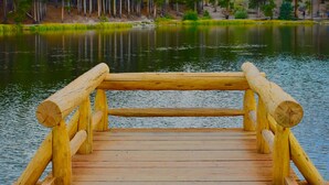 A wooden dock extending into a calm lake surrounded by a forest and mountains. - Quality Inn near Rocky Mountain National Park (Estes Park)