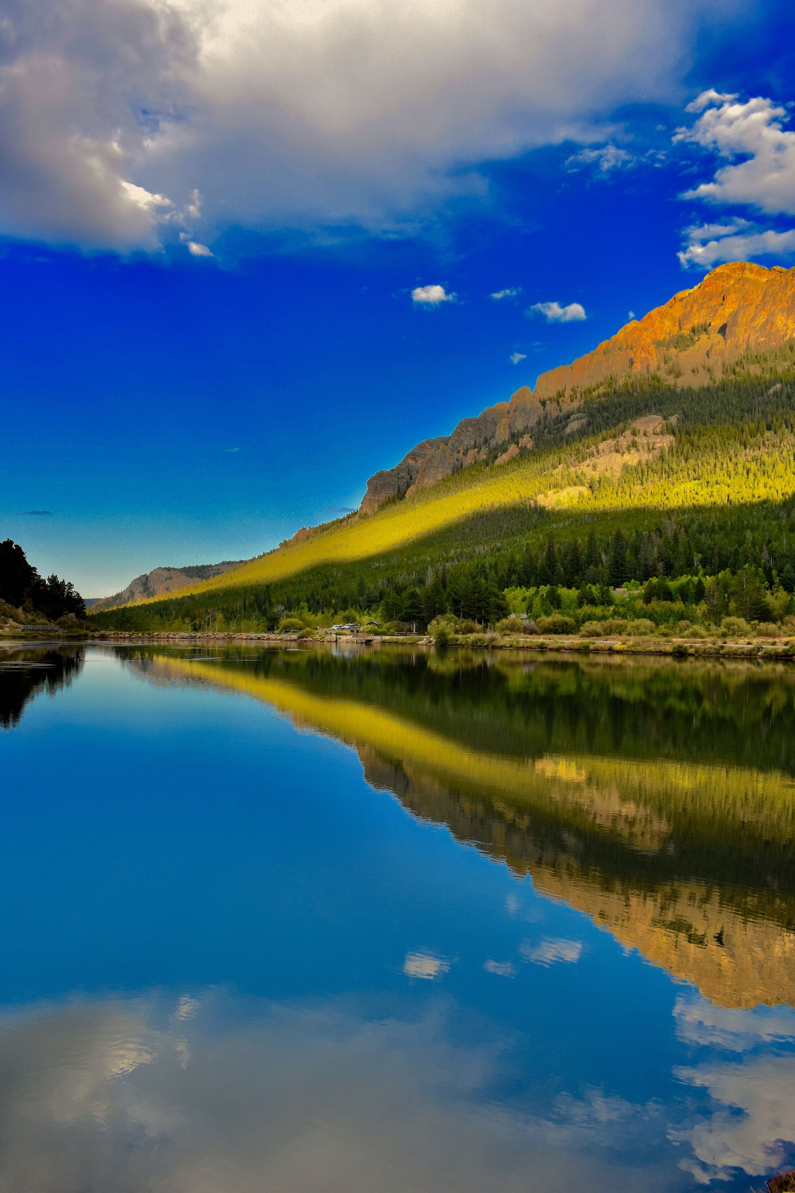 Un lago tranquilo que refleja una cadena montañosa bajo un cielo despejado.
