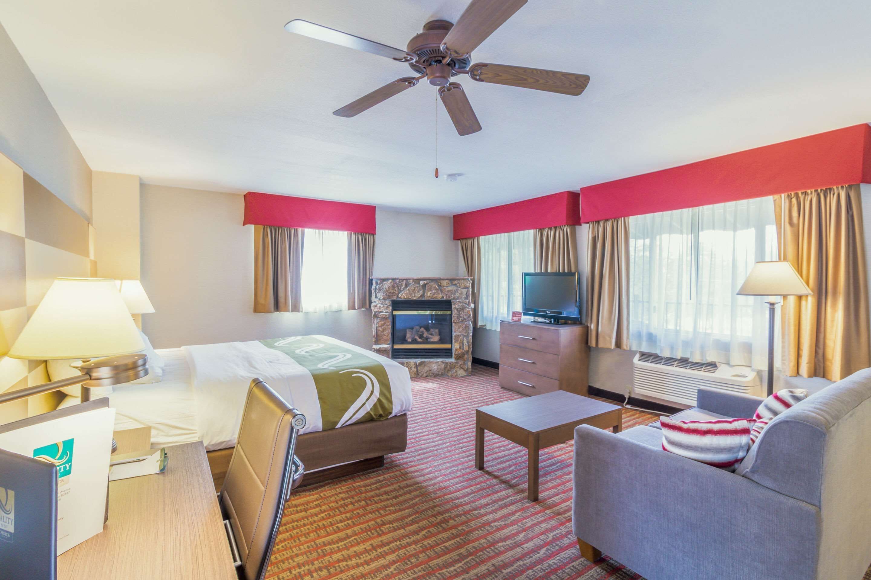 Una camera d'albergo con un letto, una televisione, un camino, una scrivania e un divano.