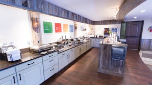 A long, narrow kitchen with white cabinets, a wooden countertop, and a built-in coffee station. - Quality Inn near Rocky Mountain National Park (Estes Park)