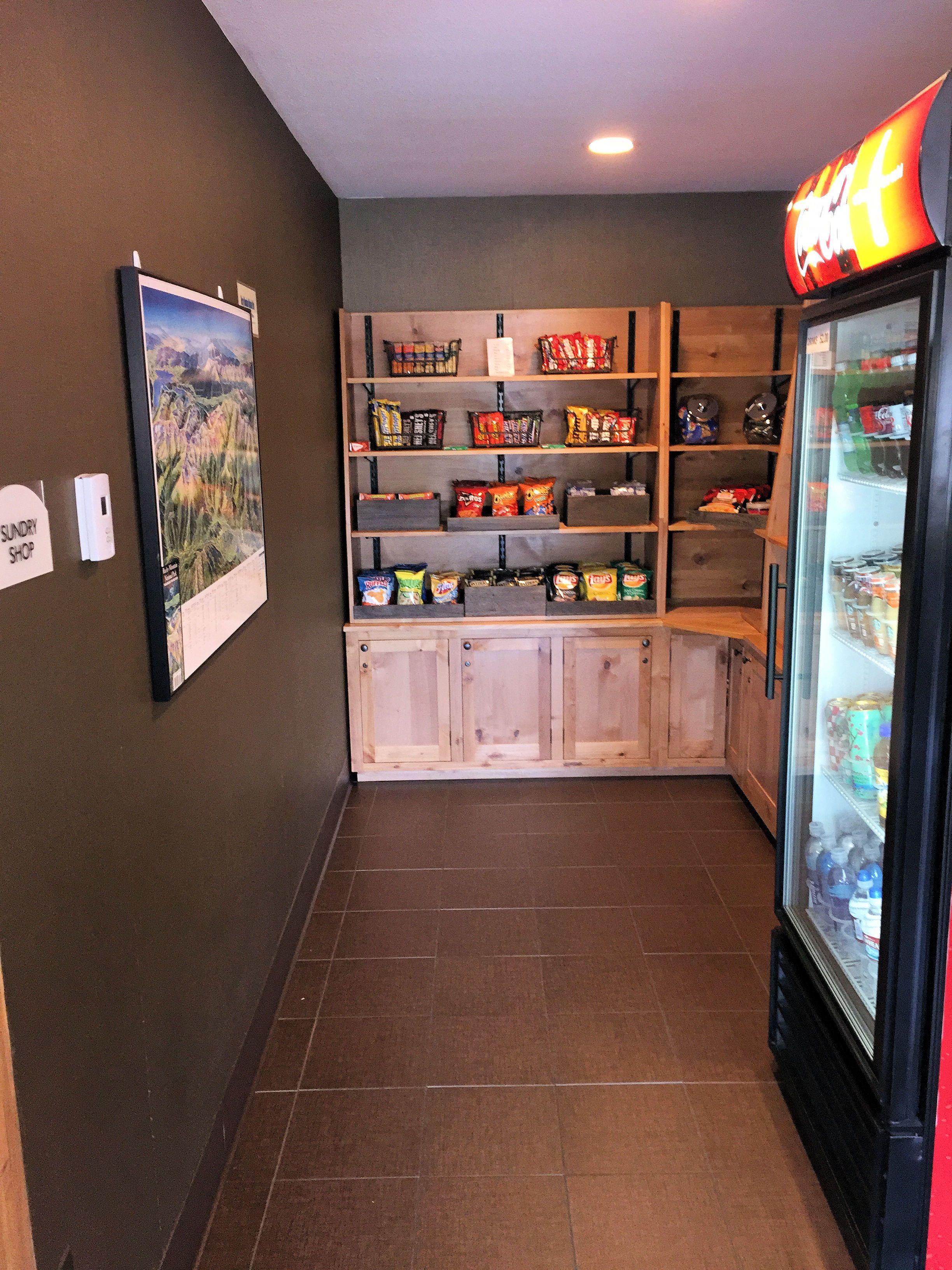 A snack bar with shelves stocked with various snacks and a refrigerator filled with beverages.