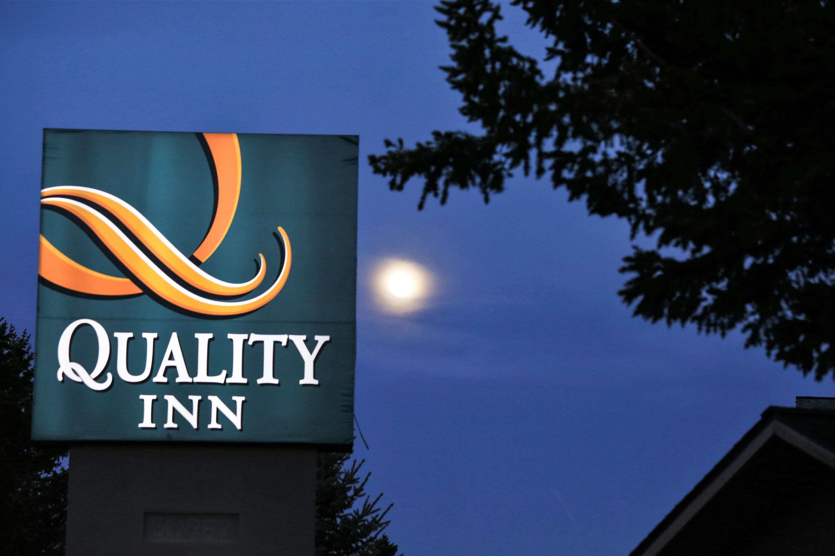 Un letrero de Quality Inn, con un logotipo estilizado y el nombre en letras blancas sobre un fondo oscuro.