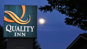 Un letrero de Quality Inn, con un logotipo estilizado y el nombre en letras blancas sobre un fondo oscuro.