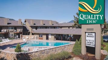 A Quality Inn hotel with a pool area, lounge chairs, and a sign for the Wool Market Events Complex.