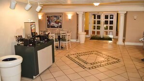 A reception area with a counter, chairs, a painting, and a patterned floor. - The Grand by Capital O Texarkana I-30 (Texarkana)