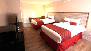 A hotel room with two beds, a desk, and a television. - The Grand by Capital O Texarkana I-30 (Texarkana)