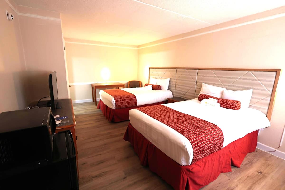 Quarto de hotel com duas camas, uma escrivaninha e uma televisão.