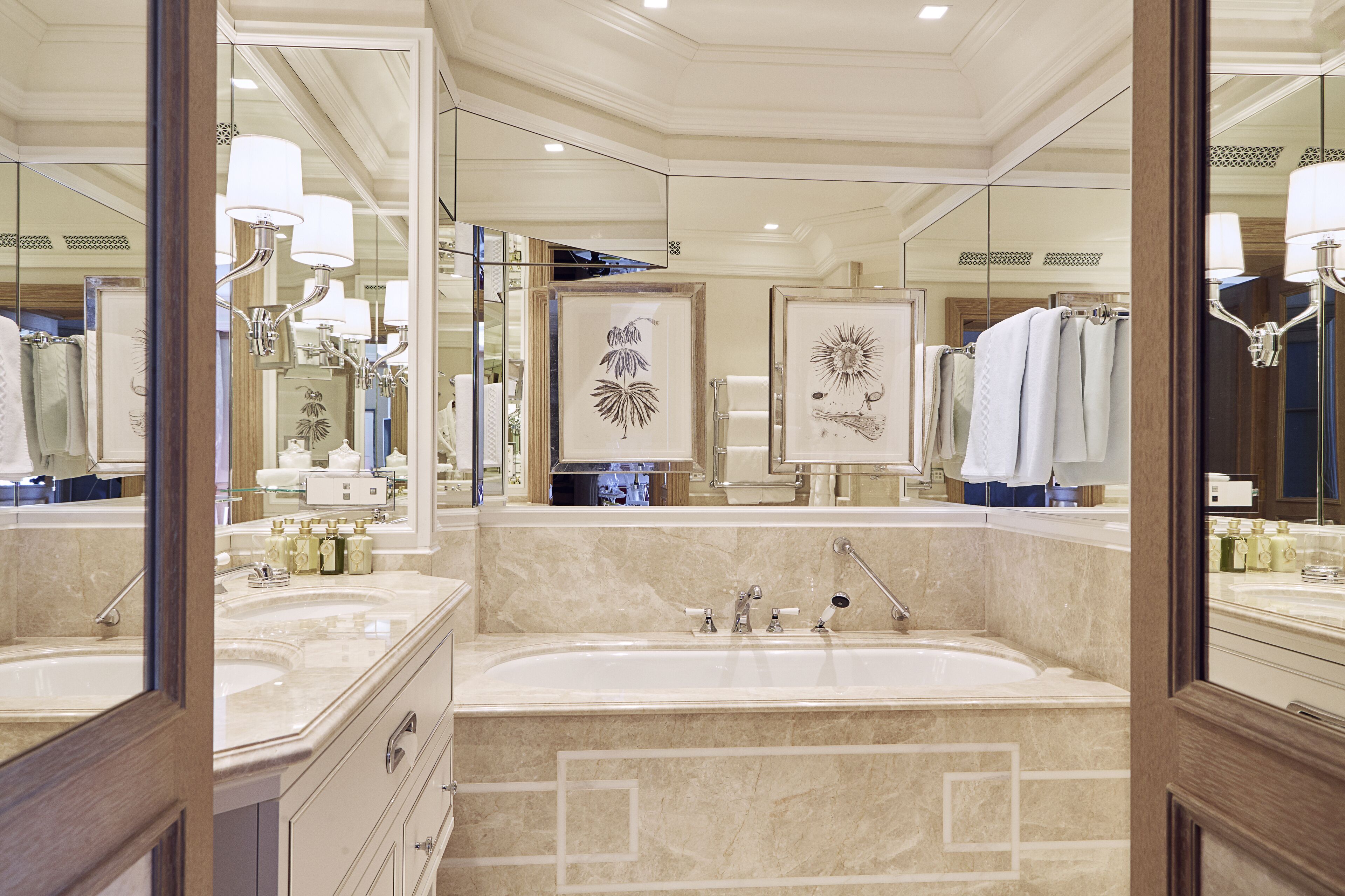 Une salle de bain luxueuse dotée d’un grand miroir, de plusieurs lavabos et d’une baignoire.