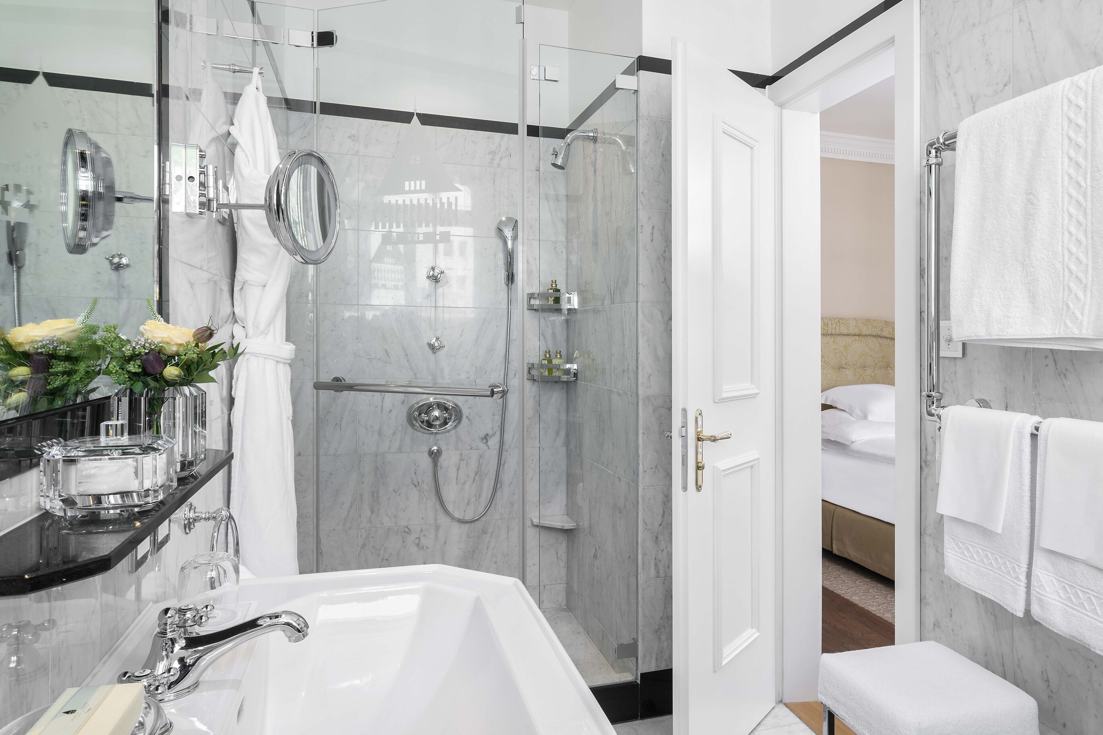 A modern bathroom with a glass-enclosed shower, a white bathtub, and a vanity with a mirror.