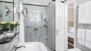 A modern bathroom with a glass-enclosed shower, a white bathtub, and a vanity with a mirror.