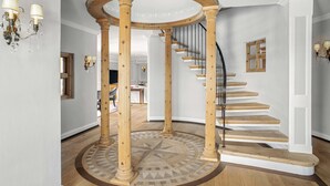A grand staircase with a wooden circular column structure, a wooden floor, and a white wall.