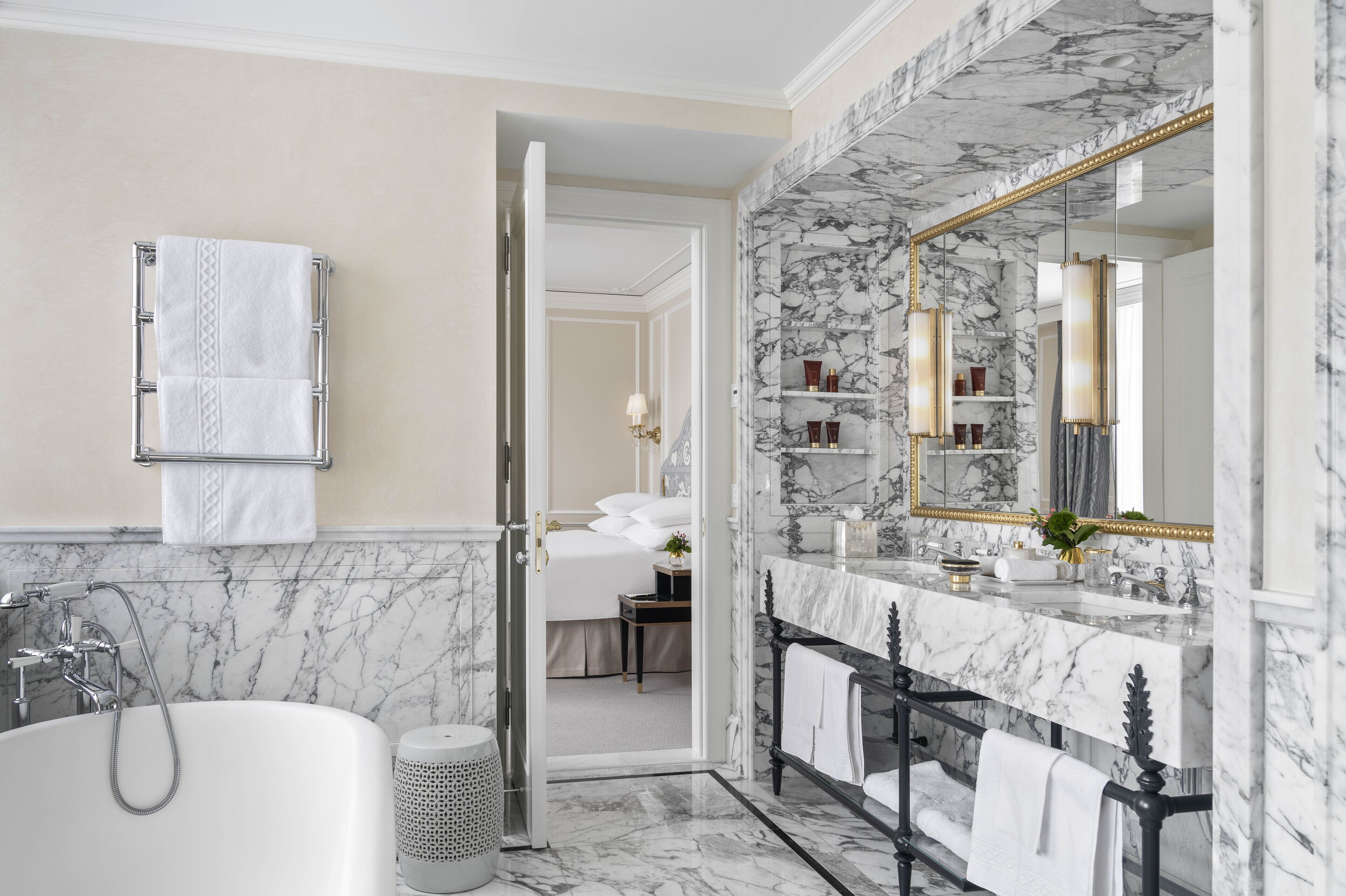 A modern bathroom with a marble sink, a large mirror, and a bathtub.