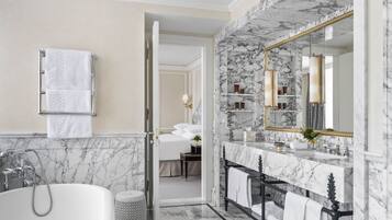A modern bathroom with a marble sink, a large mirror, and a bathtub.