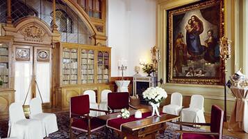 A grand room with a large painting, a fireplace, and a bookshelf.