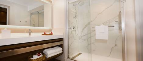 A modern bathroom with a glass-enclosed shower, a large mirror, and a wooden vanity with a shelf.