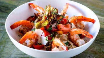 Un tazón de ensalada de camarones con lechuga, tomates y queso.