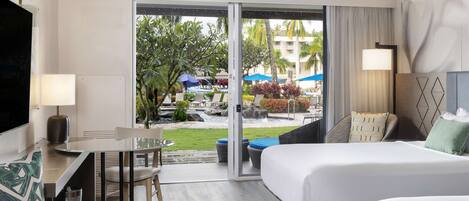 Une chambre d’hôtel équipée d’un lit, d’un bureau, d’une chaise et offrant une vue sur l’espace extérieur de la piscine.
