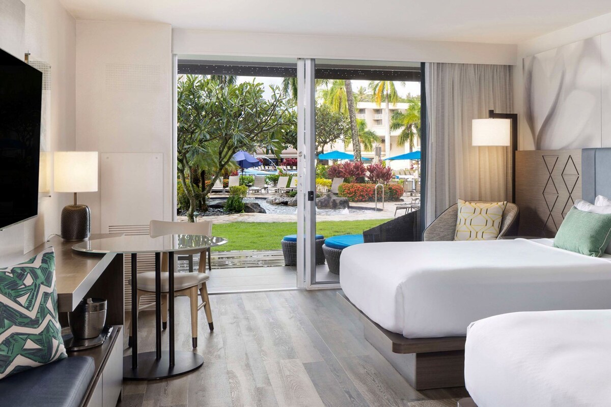 A hotel room with a bed, a desk, a chair, and a TV.