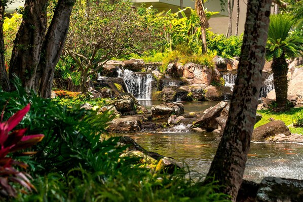 Un jardín exuberante con una cascada, rocas y plantas tropicales.