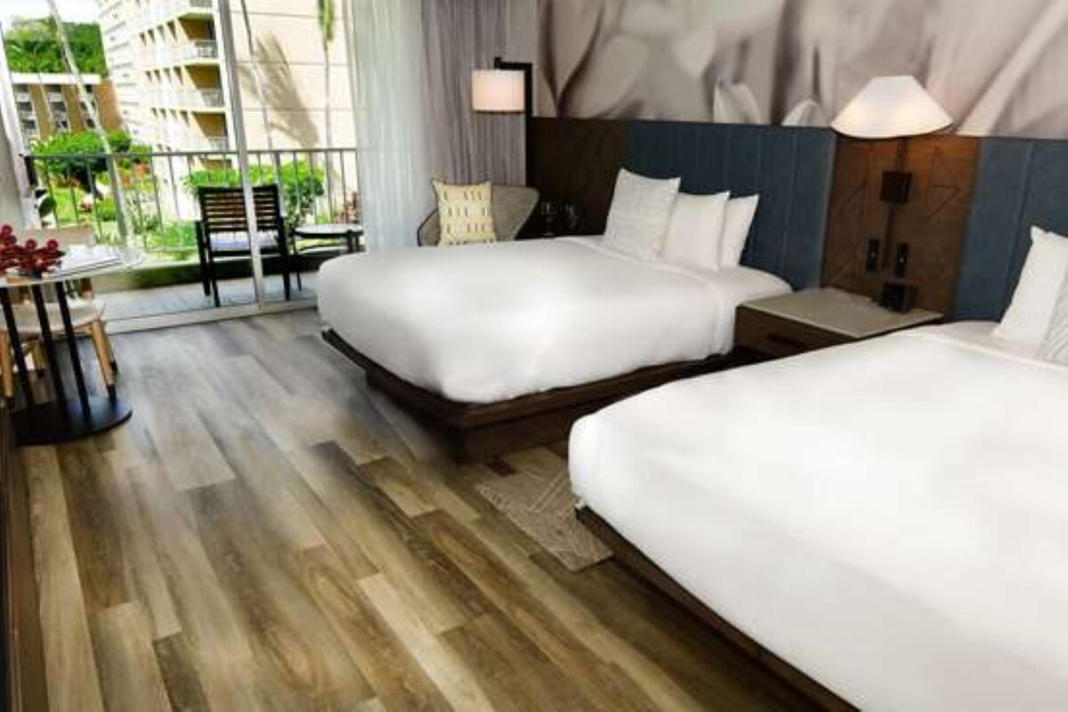 A hotel room with two beds, a small table, and a view of the outdoors.