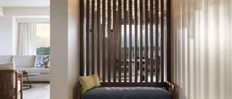 A modern living room with a wooden partition, a sofa, and a bench with cushions.