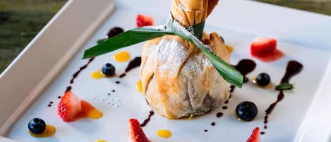 A dessert plate with a pastry centerpiece, strawberries, blueberries, and chocolate sauce.