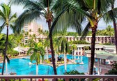 A resort with multiple swimming pools surrounded by palm trees and a building with balconies.